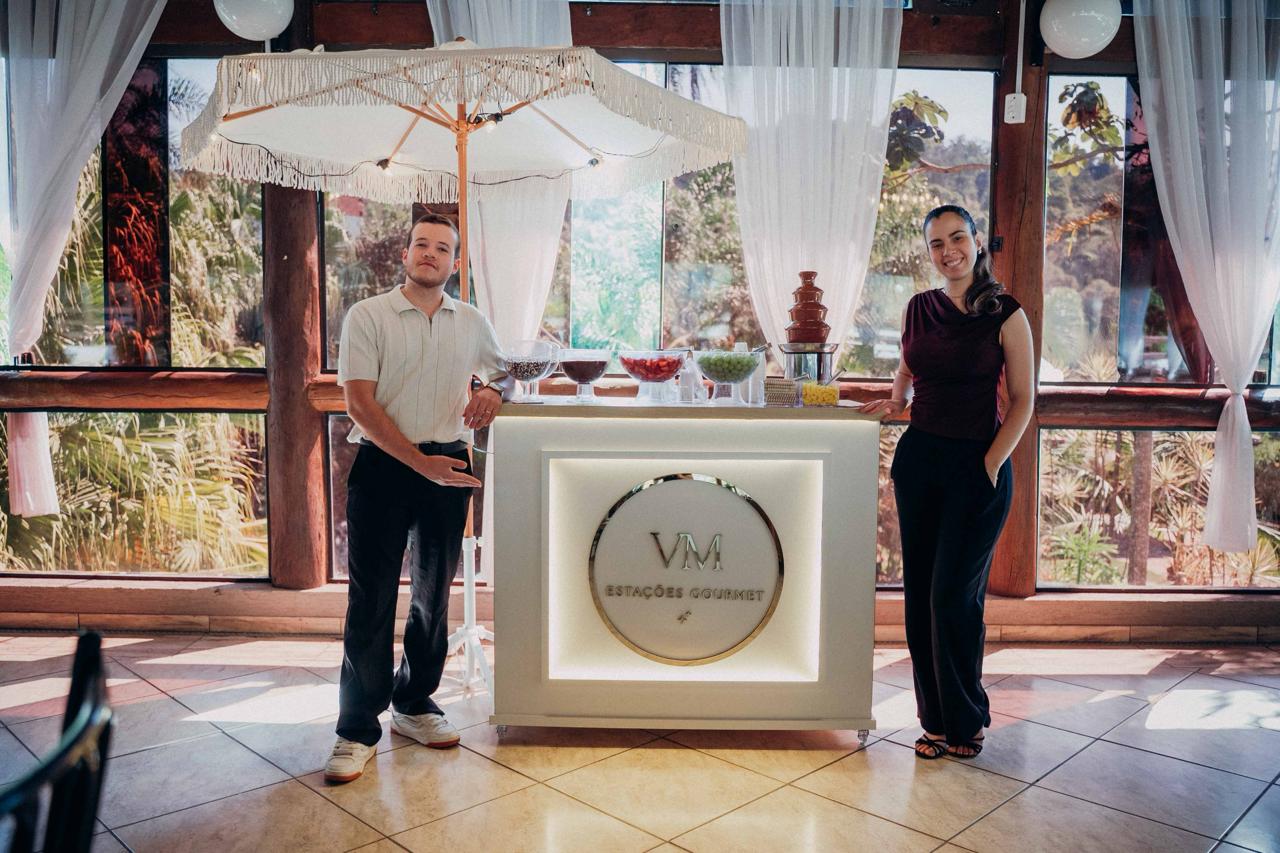 Equipe da VM Estações Gourmet ao lado do carrinho de fondue com cascata de chocolate